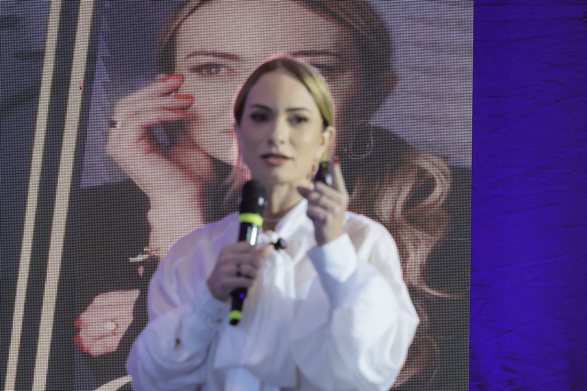 Dra. Carla Assis falando ao microfone no palco