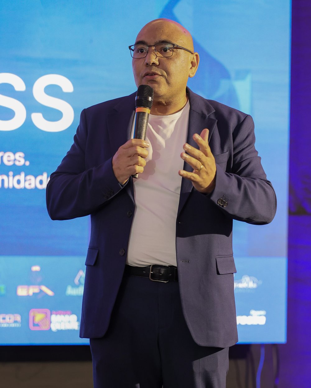 João Alves falando ao microfone no palco do Brasil Business Day
